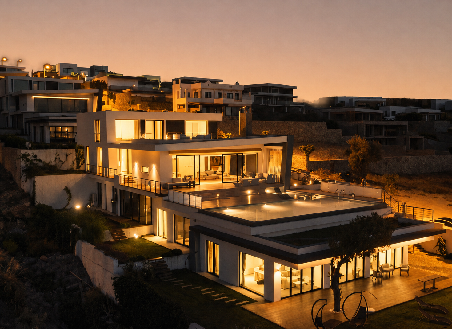 Bodrum'da Marinhill Luxury Villas, akşam ışığında modern bir yamaç evi; aydınlatılmış iç mekânlar, terasları ve sonsuzluk havuzu