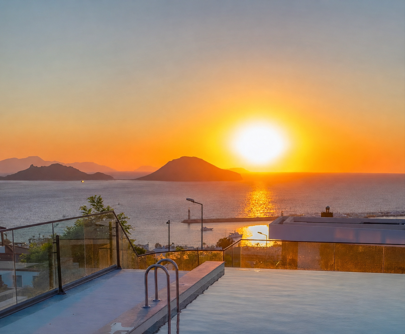 A sunset view over the Aegean sea from a villa infinity pool terrace, with warm orange light and distant hills