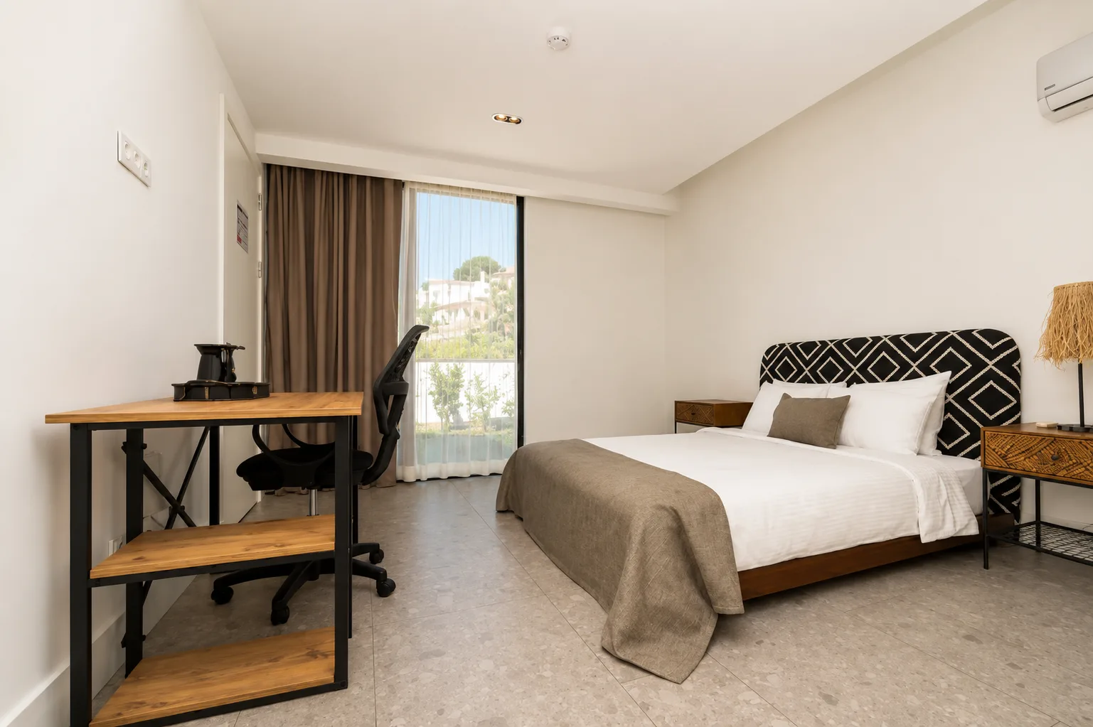 Garden View room with a patterned headboard, a wooden desk and a balcony door facing the garden